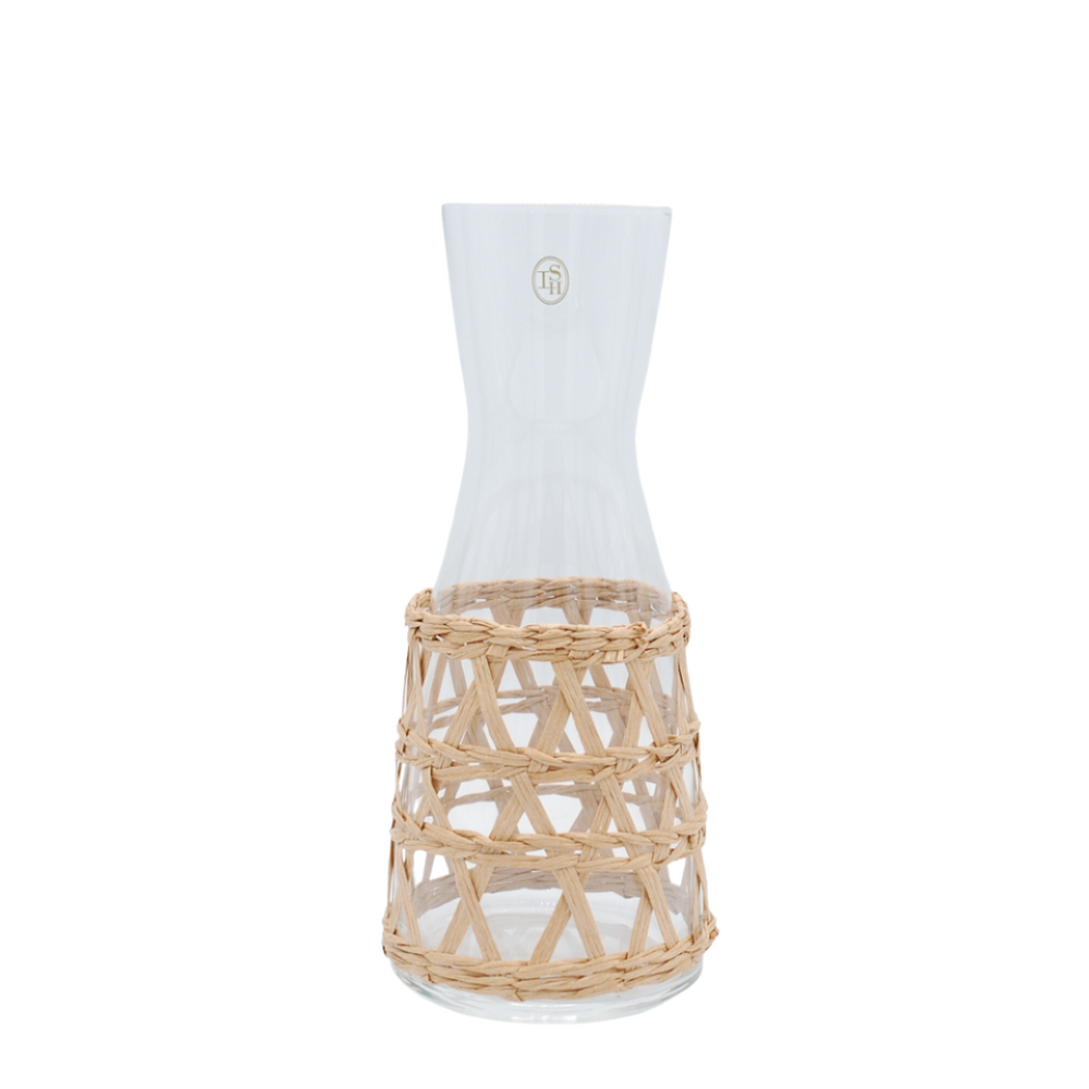 A clear glass carafe with a natural beige woven seagrass wrap around the body.