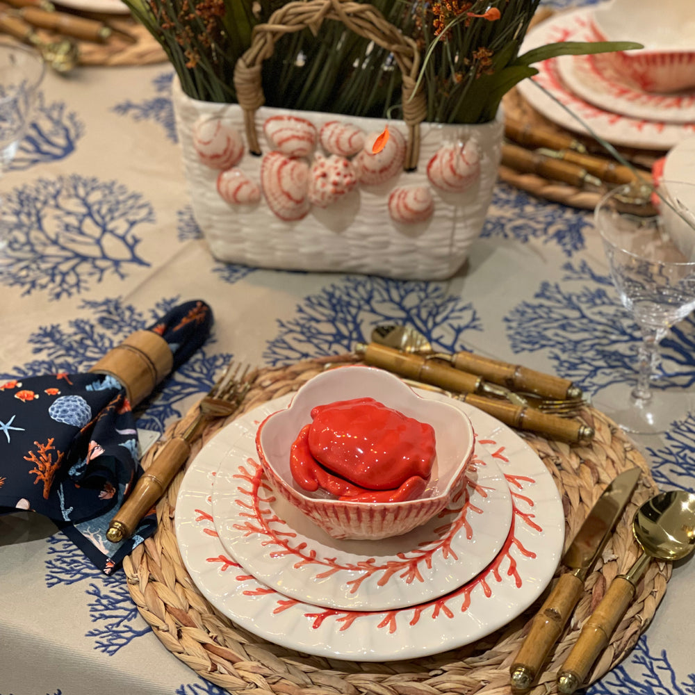 Decorative table setting with seashell-themed decor and a bowl of red food.