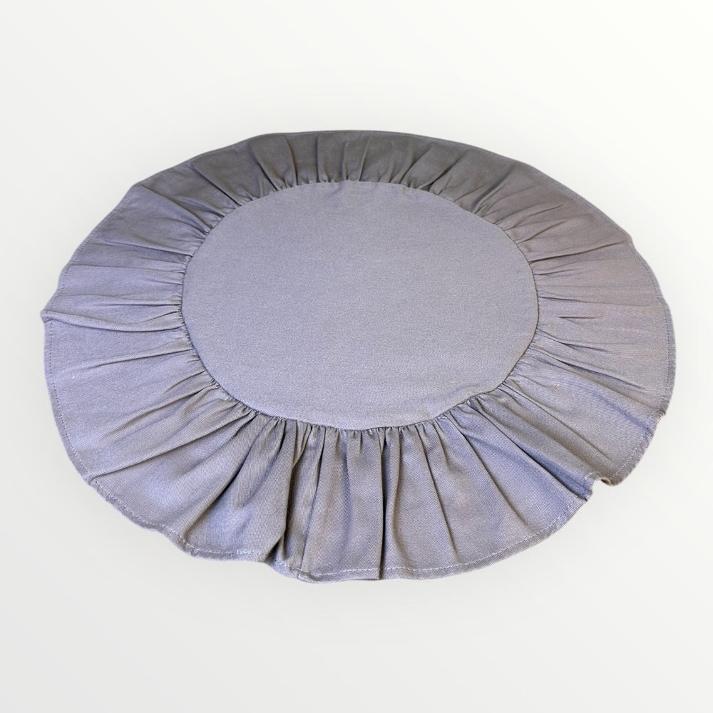 Round gray cushion with ruffled edges on a white background