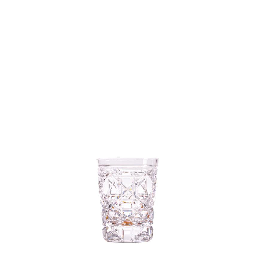 A clear crystal shot glass with a geometric pattern.