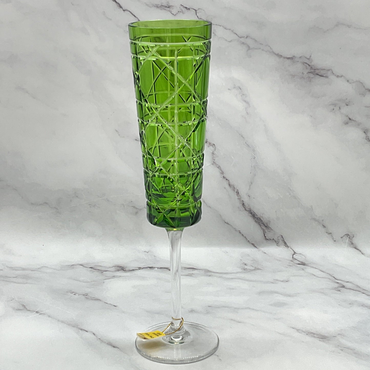 A green engraved royal crystal champagne glass with a geometric pattern.