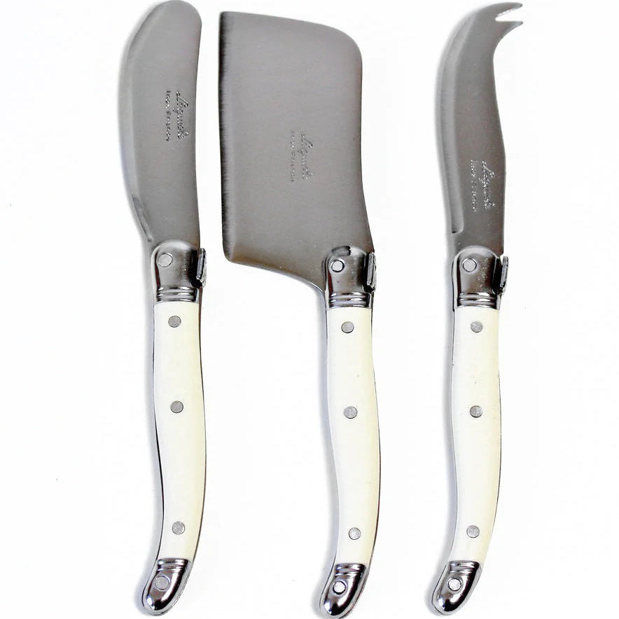 A set of three Laguiole mini cheese knives with ivory-colored acrylic handles, including a hard cheese cutter, a soft cheese spreader, and a fork-tipped knife, packaged in a brown cardboard box.