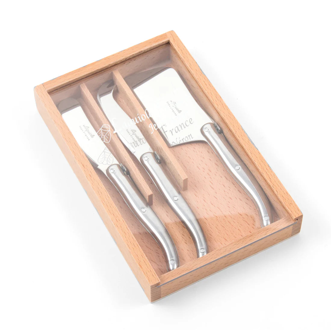 A wooden box with a sliding acrylic lid containing three stainless steel mini cheese tools with wooden handles.