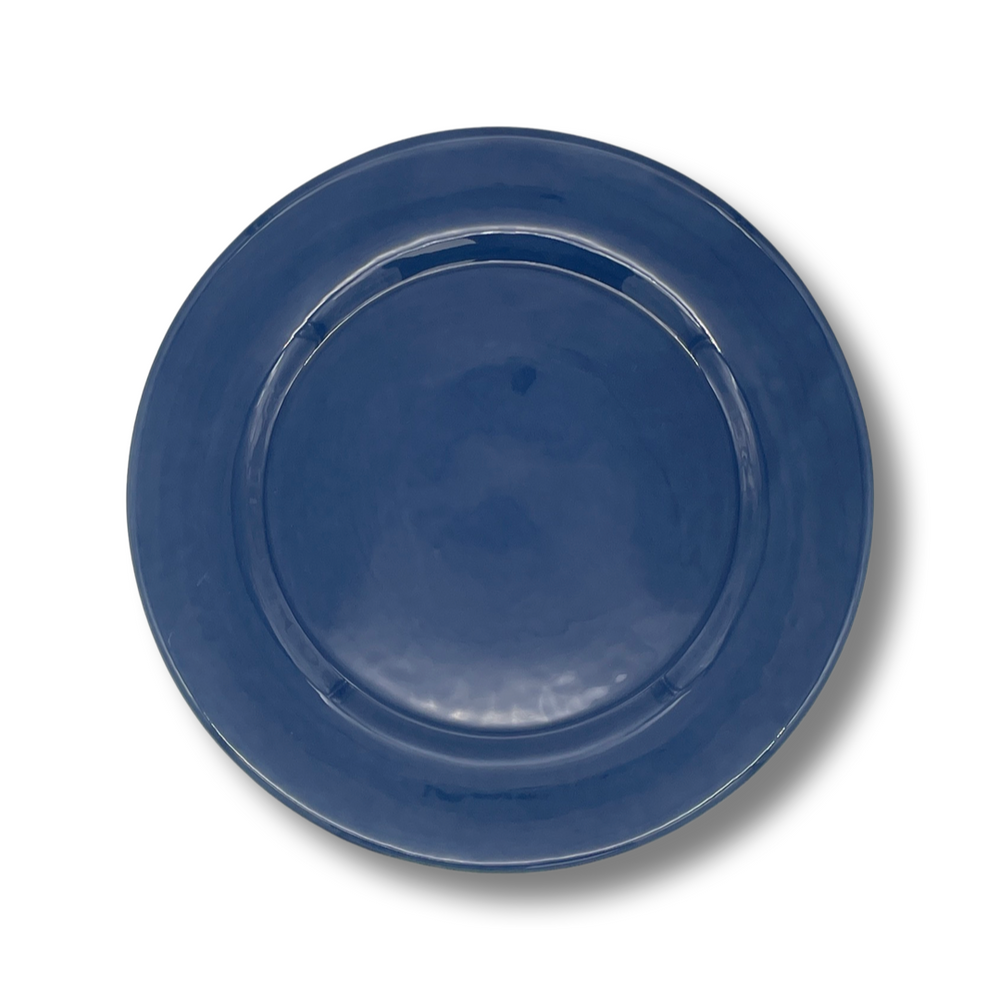 A royal blue ceramic charger plate with a scalloped edge and beaded detailing along the rim.