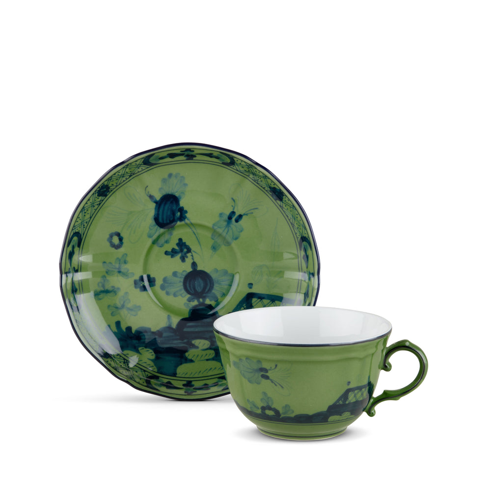 A green porcelain tea cup with floral decoration, accompanied by a matching tea saucer, both with a malachite color pattern.
