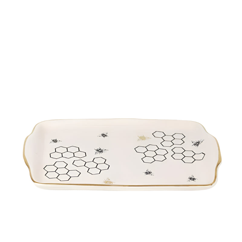 A beige ceramic serving platter with a honeycomb pattern design in the center, featuring small black bees