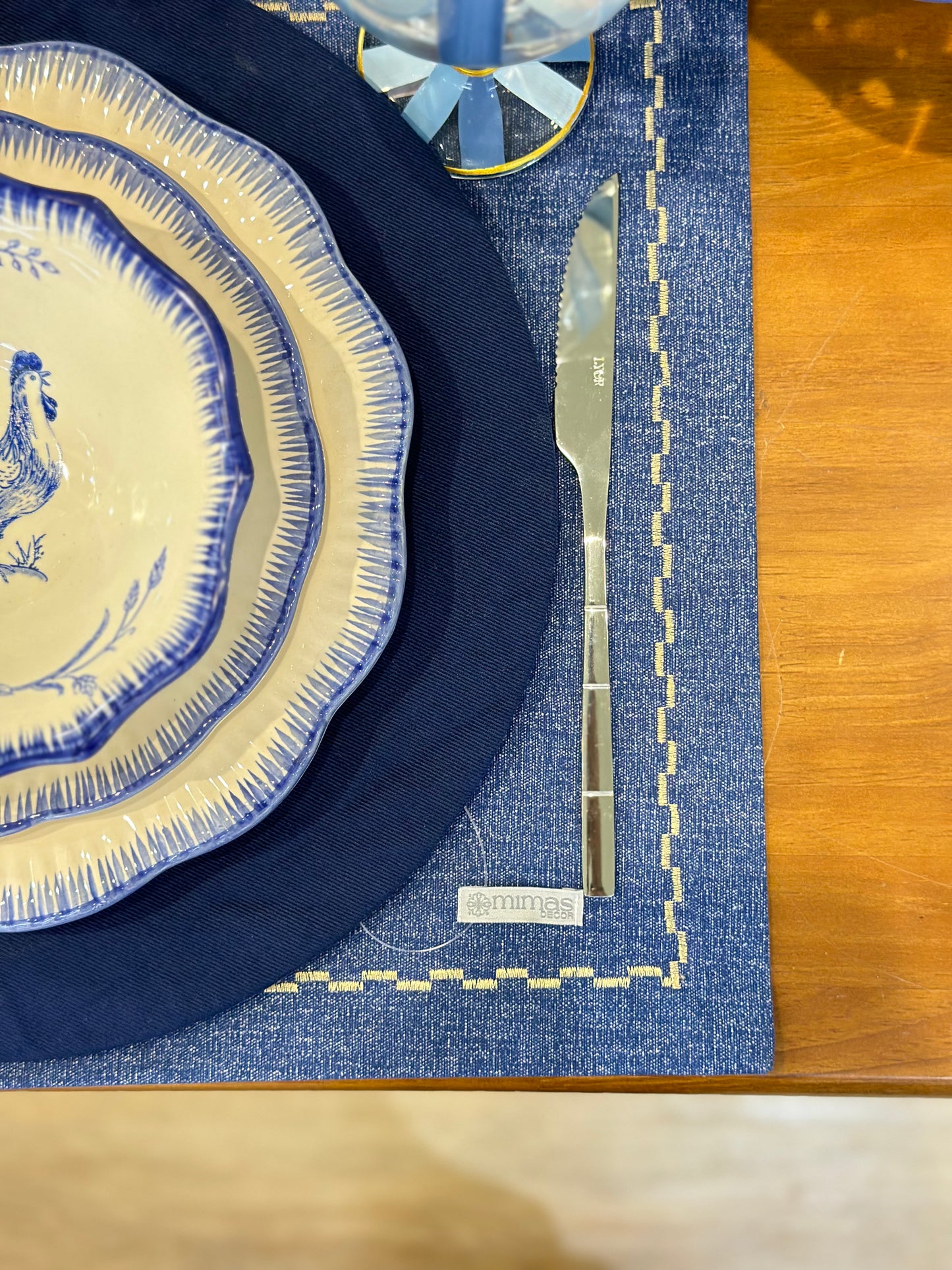 Navy blue and white ceramic plates with a silver knife on a blue placemat.
