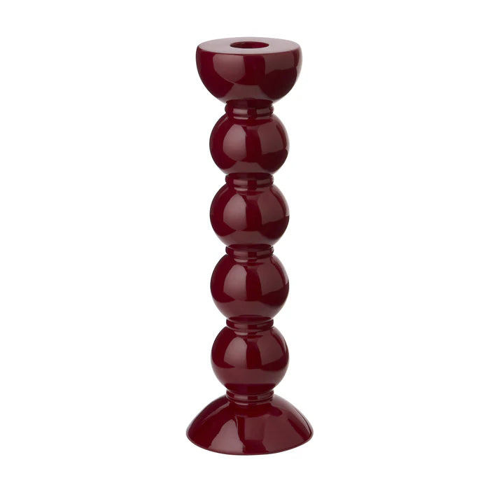A tall cherry red lacquered bobbin-shaped candlestick with a smooth finish and polished base.