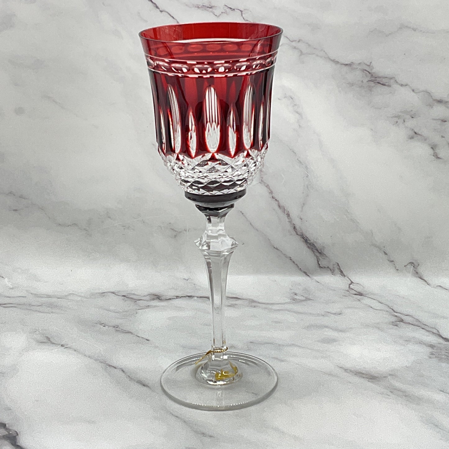 A red crystal water glass with white overlay patterns.