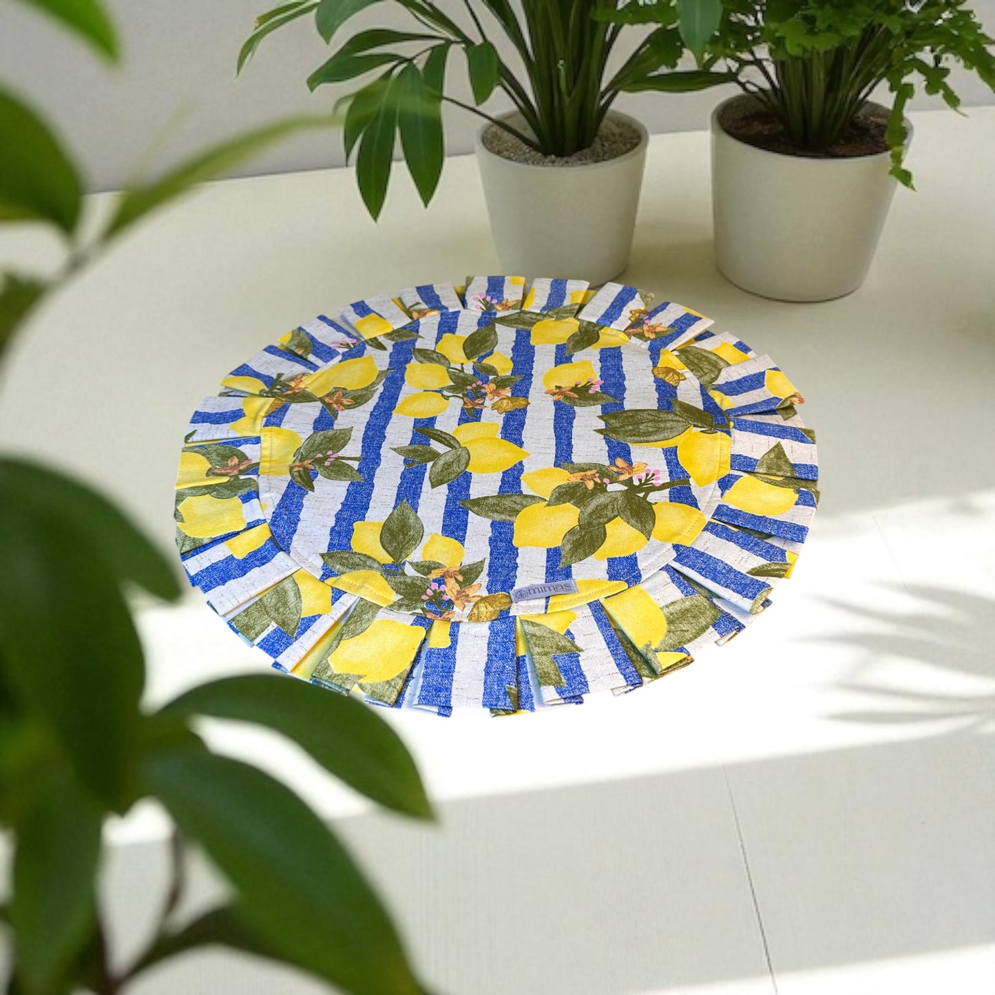 Round table mat with lemon design on a white surface with plants