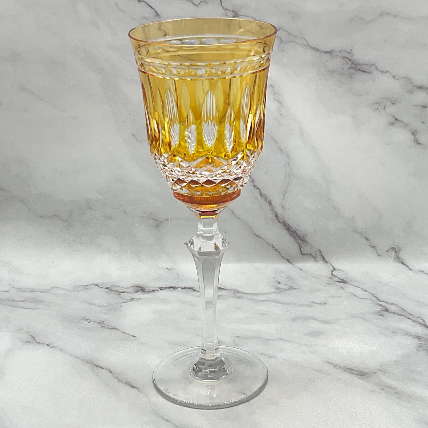 A stemware glass with an amber-colored bowl and clear stem, part of the Serenate Crystal collection.